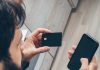 man in gray sweater holding black smartphone