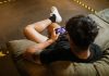 man in black crew neck t shirt playing mobile game
