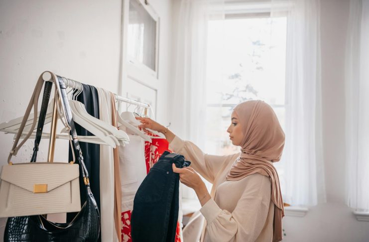woman wearing hijab standing in front of a clothing rack